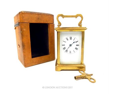 A 20th CENTURY GILT BRASS CARRIAGE CLOCK AND LEATHER TRAVEL CASE; having four bevelled glass panels and black Roman number ma