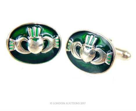 A pair of sterling silver and green enamel cufflinks, each cufflink set with a central oval plaque depicting a silver heart e