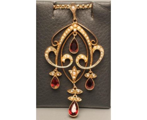AN EDWARDIAN 9CT GOLD ART NOUVEAU PENDANT, the open scroll panel set with seed pearls and hung with four tear cut garnets, 2 