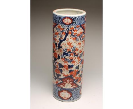 AN IMARI PORCELAIN STICK STAND, c.1900, of plain cylindrical form, painted in typical palette with trees, roots and fencing, 