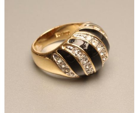 A 14KT GOLD COCKTAIL RING, the wide domed panel with black enamel wrythen stripes alternating with five pave set diamond pane