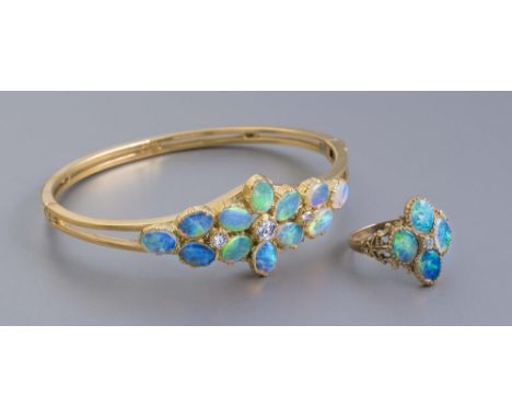 AN OPAL AND DIAMOND STIFF HINGED BANGLE, the upper section centred by an elongated cluster of twelve cabochon polished opals 