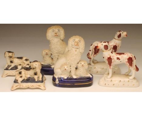 A PAIR OF VICTORIAN STAFFORDSHIRE POTTERY SPANIEL INKWELLS, the recumbent black and white dogs each with a pup on an oblong c