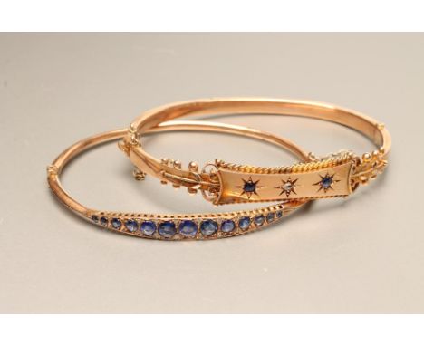 A LATE VICTORIAN 9CT GOLD STIFF HINGED BANGLE, the upper section gypsy set with a rose cut diamond flanked by two small sapph
