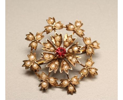 A LATE VICTORIAN 9CT GOLD SEED PEARL SET BROOCH, the cluster centred by a small facet cut garnet within a border of seed pear