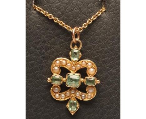 AN EDWARDIAN EMERALD AND SEED PEARL PENDANT, the quatrefoil open panel set with five open back collet vari-cut emeralds and n