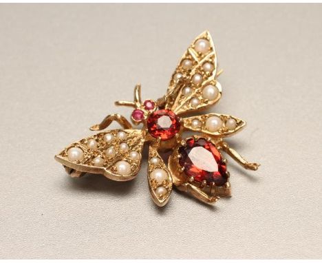 A 9CT GOLD NOVELTY FLY BROOCH with seed pearl set wings and garnet eyes, head and body, London 1987, 1" wide (Est. plus 21% p