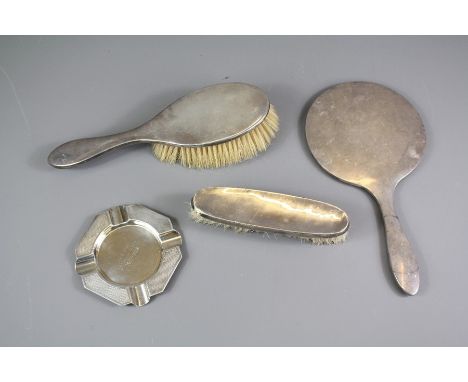 A Silver Dressing Table Trio; the trio comprising hand-held mirror and clothes brushes together with an ashtray and a "Celine