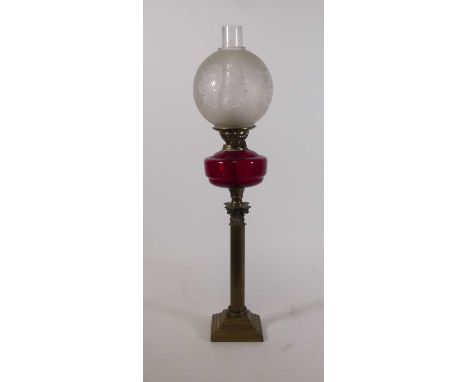 A late 19th century oil lamp, having an acid etched frosted shade over cranberry glass reservoir and Corinthian column base, 