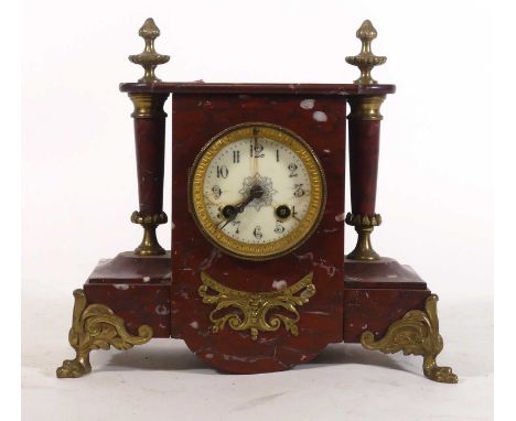 A late 19th century French rouge marble mantel clock, the enamelled dial showing Arabic numerals and twin winding holes for a