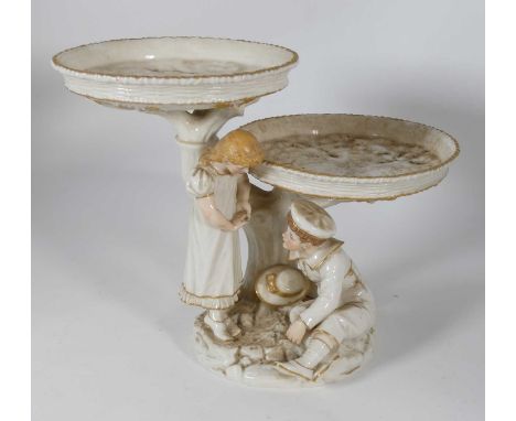 A Royal Worcester porcelain two-tier stand in the form of a boy and girl before a tree trunk, green printed and impressed mar