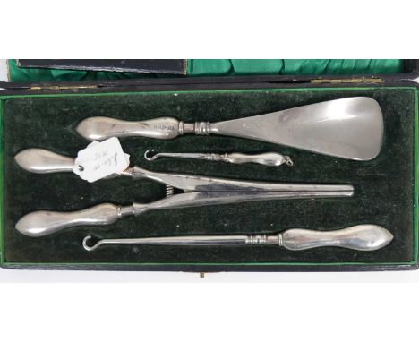 A cased set of four silver handled implements, to include glove stretchers, button hooks, and a shoehorn