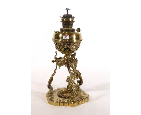 A brass oil lamp, on scrolled foliate supports with mask decoration, h.51cmNo splits or cracks in brass. Cast appears in good