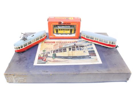 A Hamo HO gauge Tramway Set. Comprising 2 bogie tramcars in cream with grey roofs, advertising to sides – ‘Agip’, ‘Raiffeisen