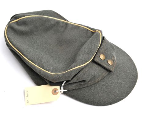 A Third Reich type grey/green ski cap, with one piece woven army eagle over cockade badge, brass buttons, and yellow piping. 