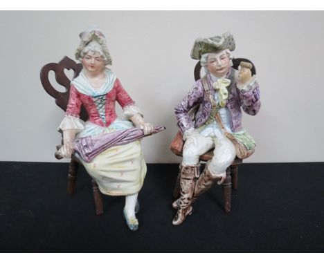 Two Continental ceramic figures, seated on pierced wood chairs 