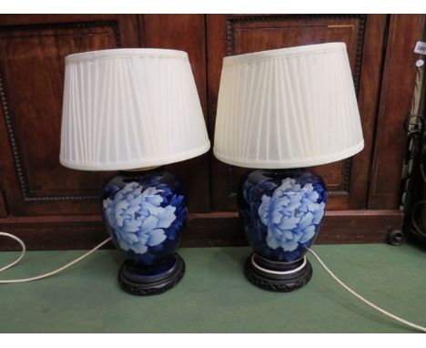 A pair of blue ceramic lamps with floral detail on wooden bases, 50cm tall