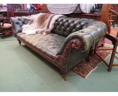 A dark green three seater Chesterfield sofa raised upon turned and ribbed legs with castors, carved detail to scrolled arms