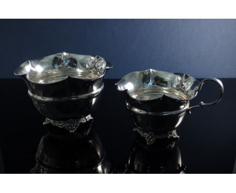 A silver sucrier and creamer, filled rim and foliate design supports 