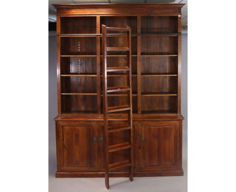 AN OAK LIBRARY BOOKCASE, fitted fifteen open shelves above three fielded panel doors, with matching set of ladder steps, &amp