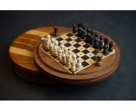 A wooden pocket chess set contained within a turned wooden case. 