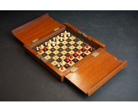 A mahogany cased travel chess set with red &amp; white bone pieces. 