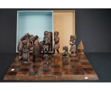 A hand carved wooden tribal chess set together with board. 