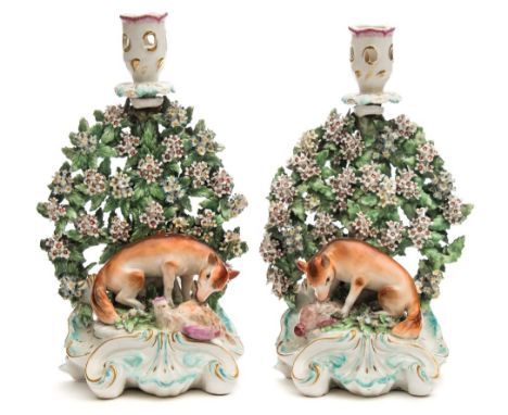 A pair of Derby porcelain fox and hen candlesticks: modelled with a seated fox devouring a hapless hen before a broad floweri
