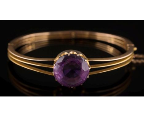 A gold and amethyst single-stone hinged bangle: the circular amethyst 15.7mm diameter and in thirteen-claw setting, with atta