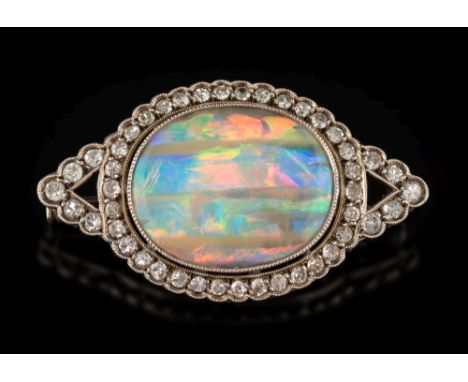 A black opal and diamond mounted oval brooch: the central oval black opal 19mm x 15mm, millegrain-set within a surround of sm