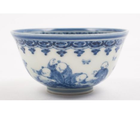 A Chinese porcelain bowl: of circular mildly everted form painted in blue with five boys and a fir tree, beneath a scroll ban