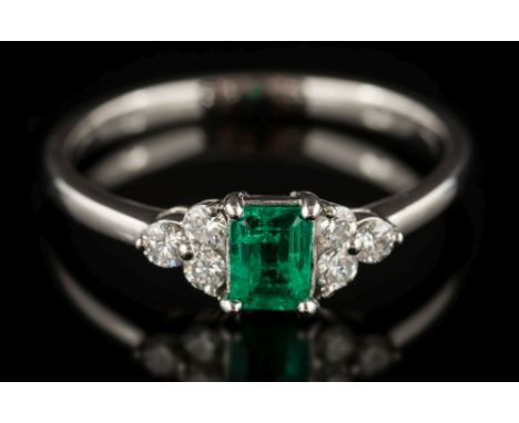 An emerald and diamond seven-stone ring: the central rectangular emerald approximately 0.30ct and between trefoil diamond clu