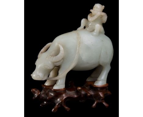 A Chinese pale celadon jade carving of a boy on a water buffalo: the boy playing a flute, the standing buffalo with head lowe