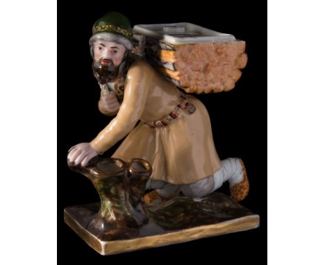 A Gardner (Moscow) porcelain desk stand: in the form of a peasant kneeling by a hollow stump supporting a bundle of logs on h