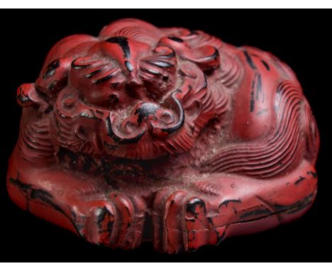A Japanese red lacquer netsuke and a carved horn netsuke: the first in the form of a sleeping tiger, 4 cm wide [some damage];