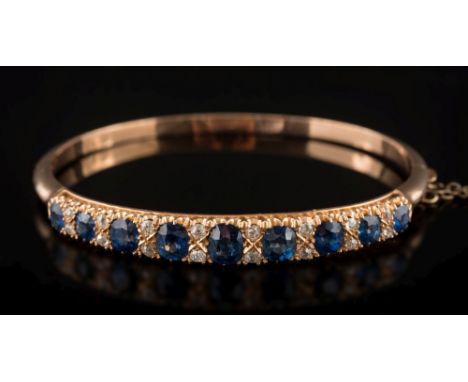 A late 19th century gold, sapphire and diamond mounted hinged bangle: with nine cushion-shaped sapphires graduated from 4.5mm