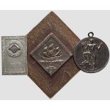 Zwei Plaketten und eine Medaille Eine geprägte Buntmetallplakette (7,5 x 7,5 cm, auf Holz