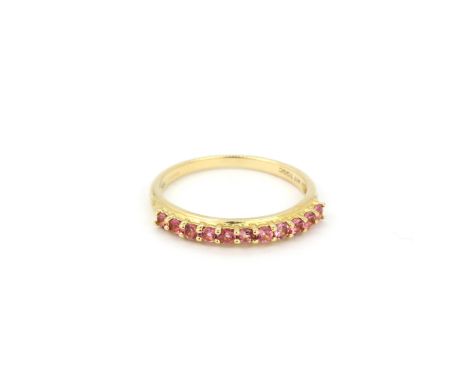 A hallmarked 9ct yellow gold pink sapphire set half eternity ring, (O).