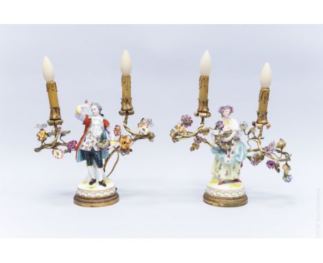 Pair of Louis XV style French porcelain figural table lamps modeled as 18th C. peasant gent and lady, each carrying bundles o