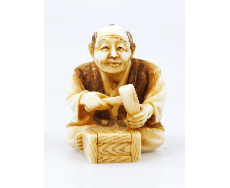 A Japanese Taisho period netsuke, of a gentleman in seated pose wearing flowing robes holding hammer before block, two charac