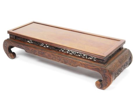 A late 19thC Chinese hardwood low altar table, the rectangular top raised on a heavily carved scroll support with an outer ge