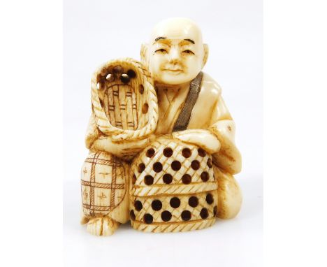 A Japanese Taisho period netsuke, formed as a gentleman in flowing robes aside baskets, two character mark beneath, 5cm high.