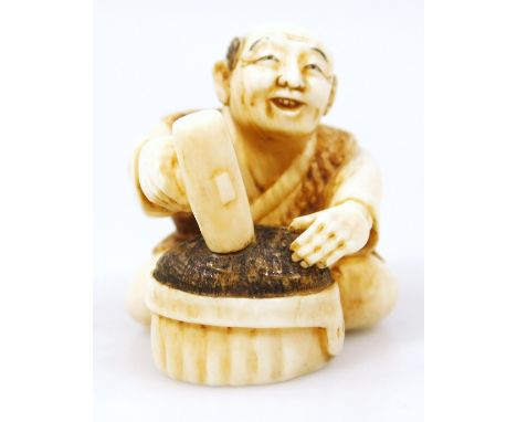 A Japanese Taisho period netsuke, of a gentleman in seated pose wearing flowing robes holding hammer before block, two charac
