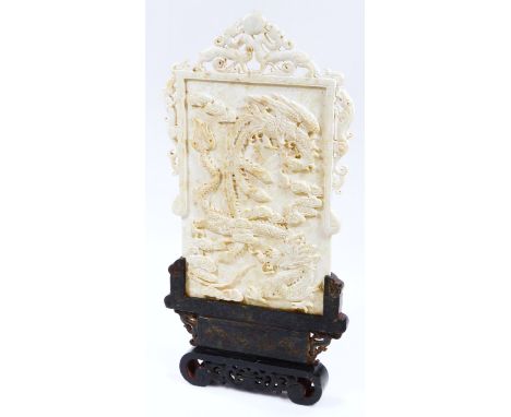 A carved Chinese stone plaque, raised with dragon, with further double dragon finial, on a shaped wooden stand terminating in