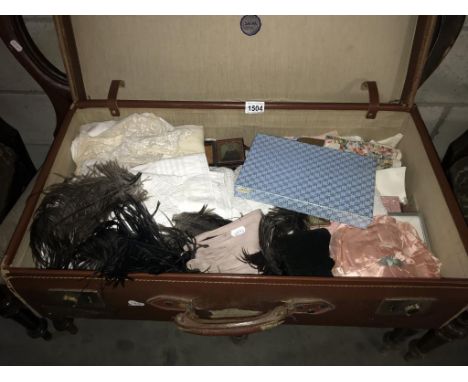 A large vinatge suitcase with vintage textiles including lace, ostrich feathers, handkerchiefs, vintage spectacles, garments 