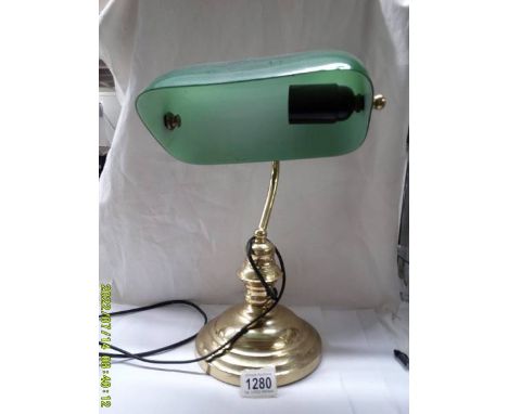 A brass bankers lamp with green glass shade.