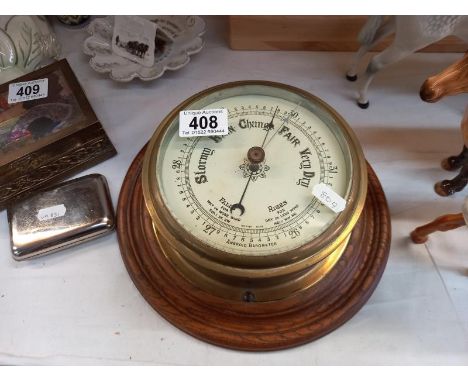 A large vintage brass ships barometer on oak mount