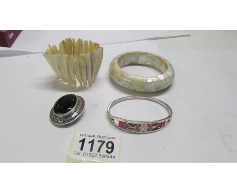 Two mother of pearl bracelets, a silver bangle and a silver mounted brooch.