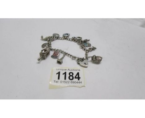 A charm bracelet dated 1958 Birmingham in silver with 12 silver charms including Lincoln Imp, dinosaur, cradle etc., some ena