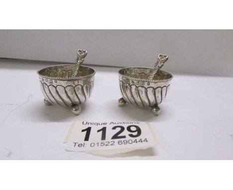 A pair of silver salts with spoons.